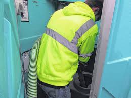 Stronghold service technician performing waste removal on a portable toilet